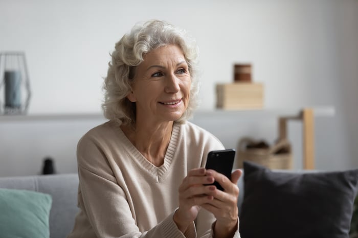 A woman with her phone, representing a patient using the Buddy Healthcare app for instructions and communication in the TAYS and Valkeakoski hospitals project