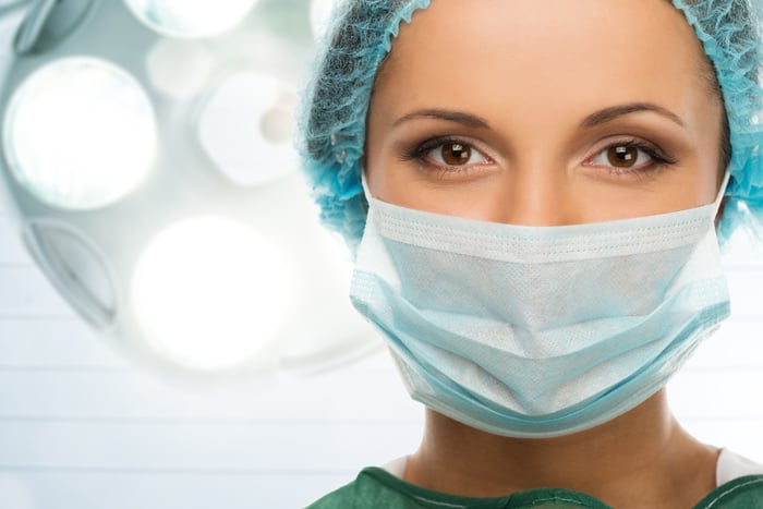Medical professional in scrubs and surgical mask